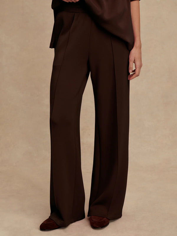 Brown wide-leg pants worn by a person on a beige background