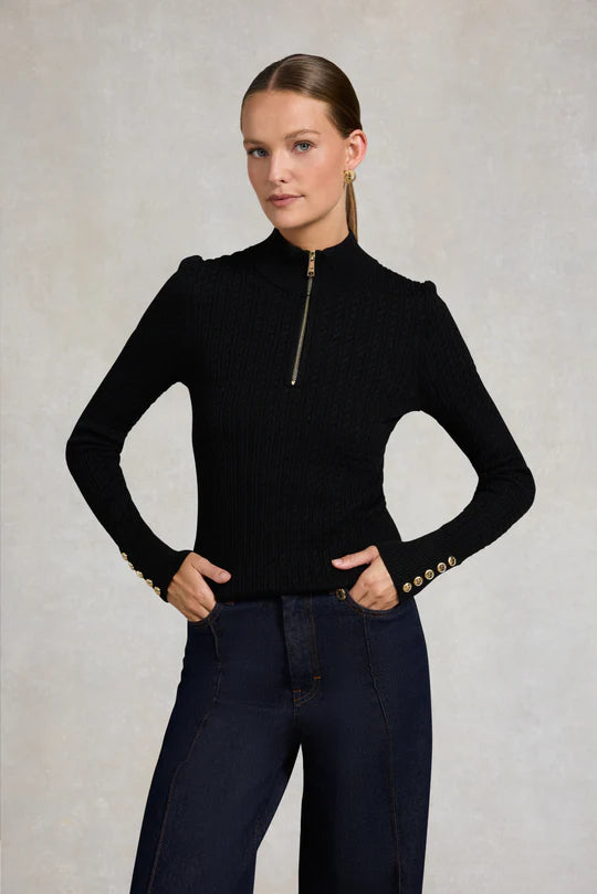 Person wearing a black long-sleeve top and navy wide-leg pants against a plain background