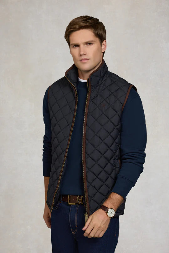 Man wearing a quilted vest over a dark shirt on a light background