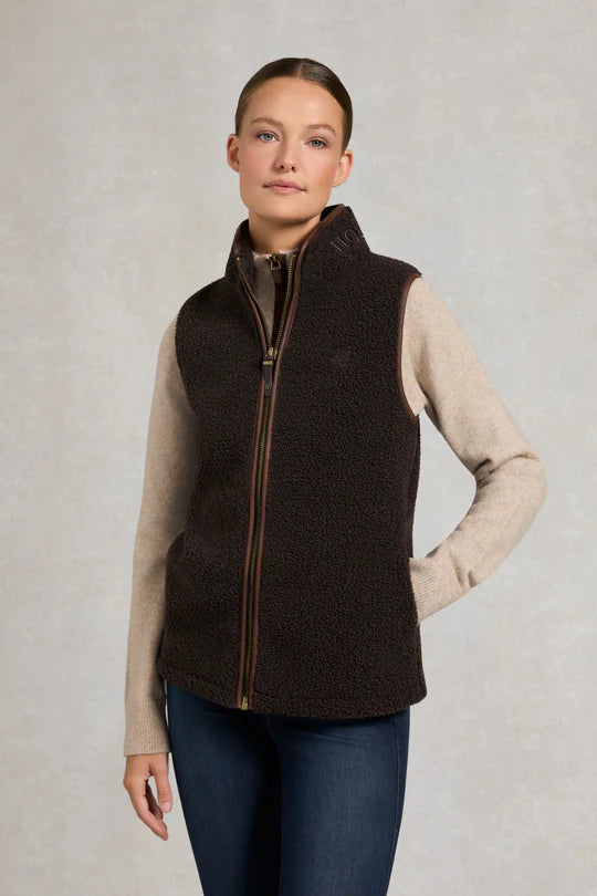 Woman wearing a brown fleece vest on a grey background