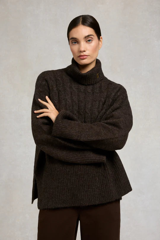 Woman wearing a brown turtleneck sweater against a plain background