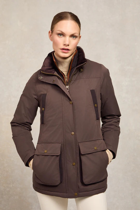 Woman wearing a brown jacket with multiple pockets on a neutral background