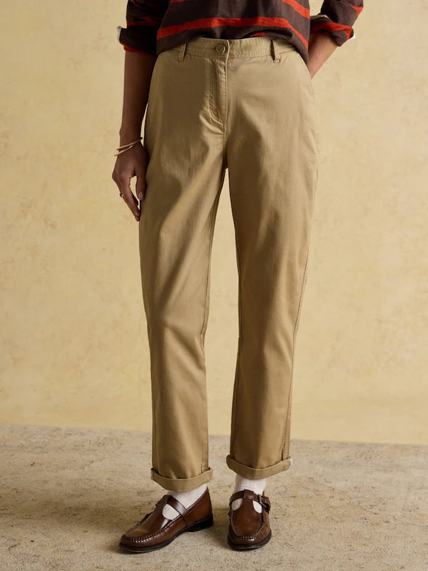 Person wearing beige pants and brown loafers on a plain background