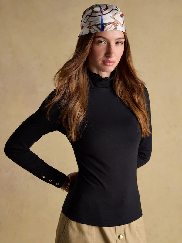 Woman wearing a black turtleneck and patterned headband against a beige background