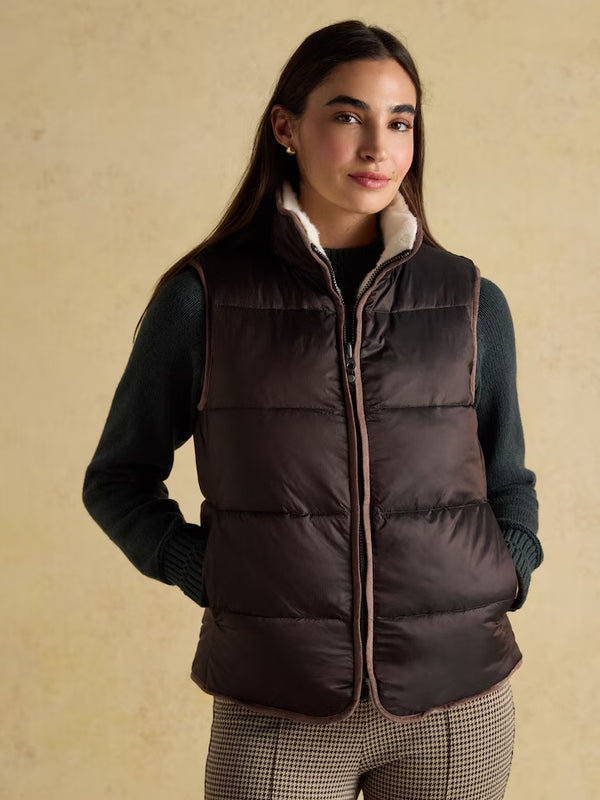 Woman wearing a brown padded gilet on a yellow background