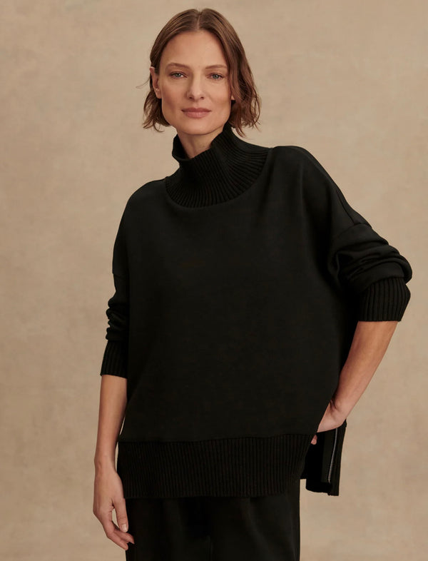 Woman wearing a black turtleneck sweater against a beige background