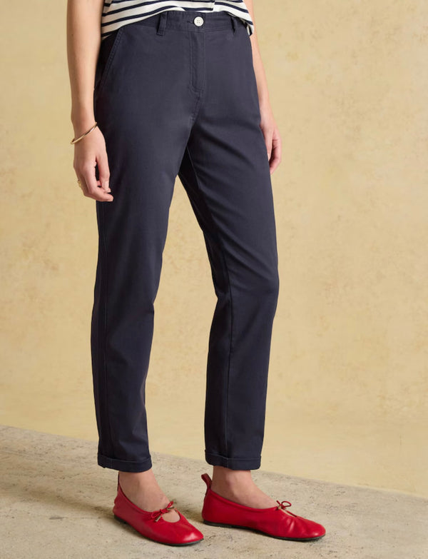 Person wearing navy pants and red shoes on a beige background