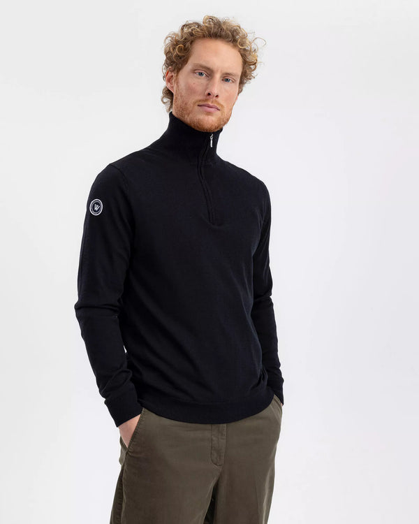 Man wearing a black turtleneck sweater with a logo on a white background