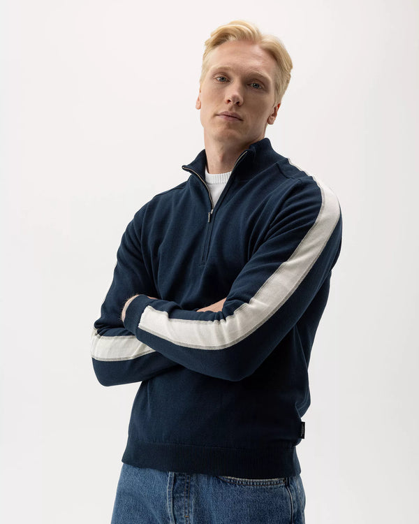 Man wearing a navy blue jacket with white stripes on a white background