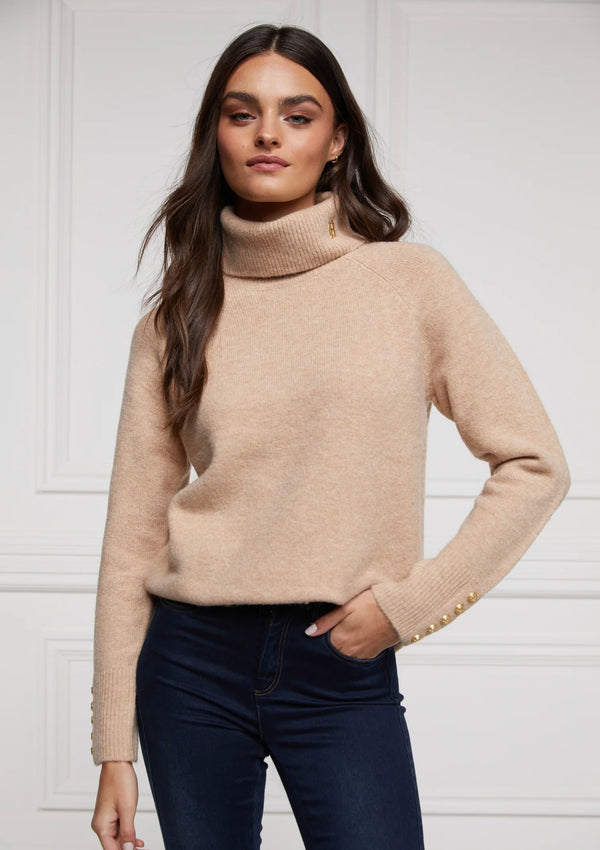 Woman wearing a beige turtleneck sweater against a white background