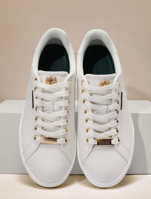 White sneakers with gold accents on a beige background