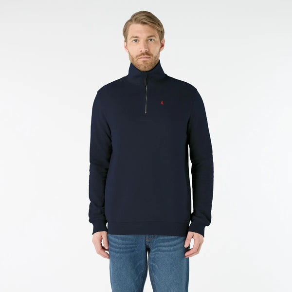 Man wearing a navy blue pullover with a small red logo on a white background