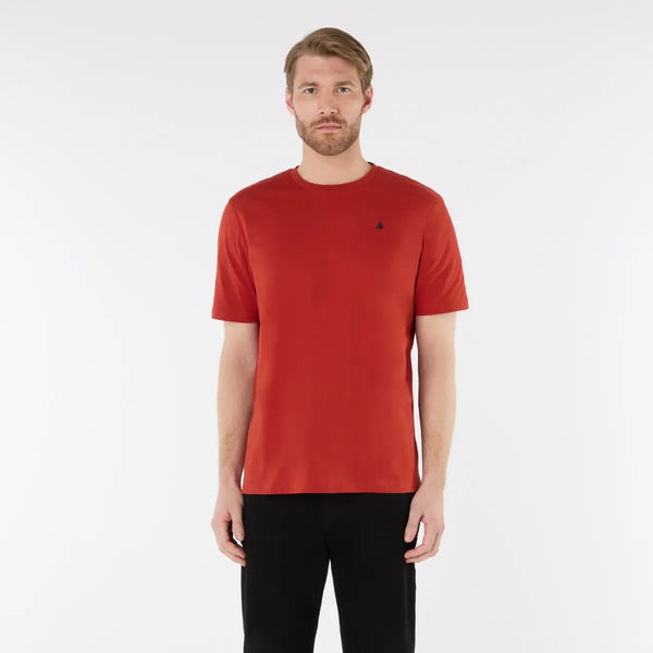 Man wearing a red t-shirt with a small black logo on a white background