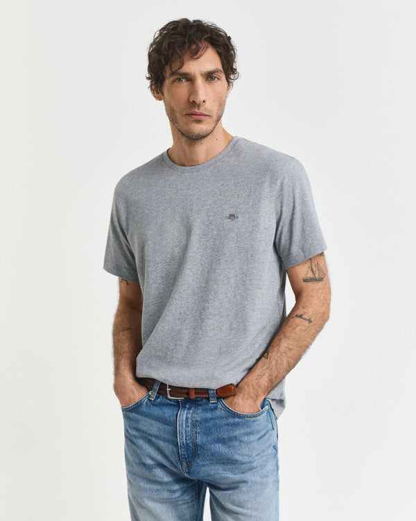 Man wearing a gray t-shirt and blue jeans on a white background