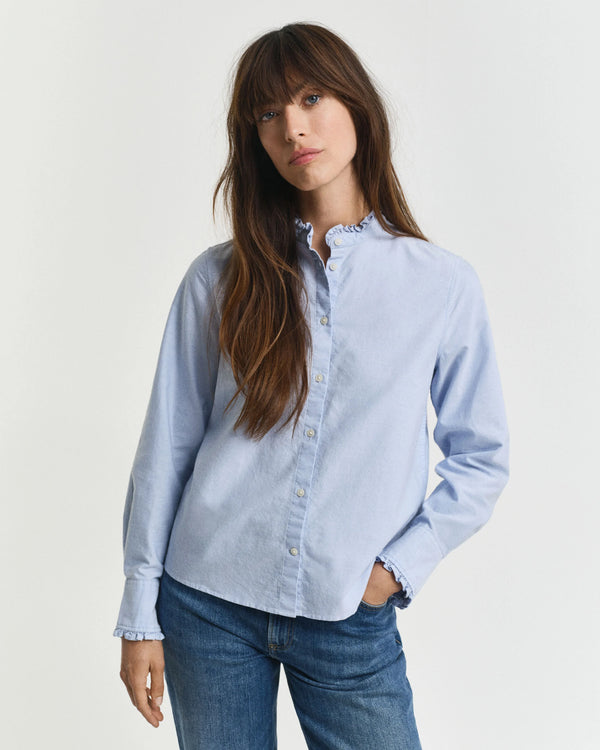 Woman wearing a light blue shirt and jeans on a plain background