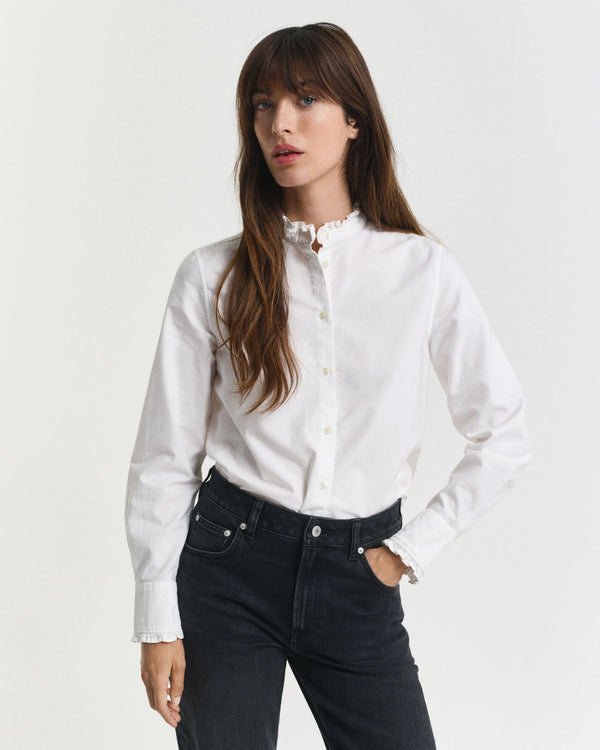 Woman wearing a white blouse with a high collar and black pants on a white background