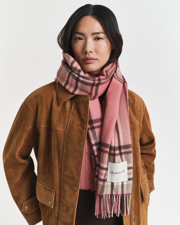 Person wearing a brown jacket and pink plaid scarf with GANT logo on a white background