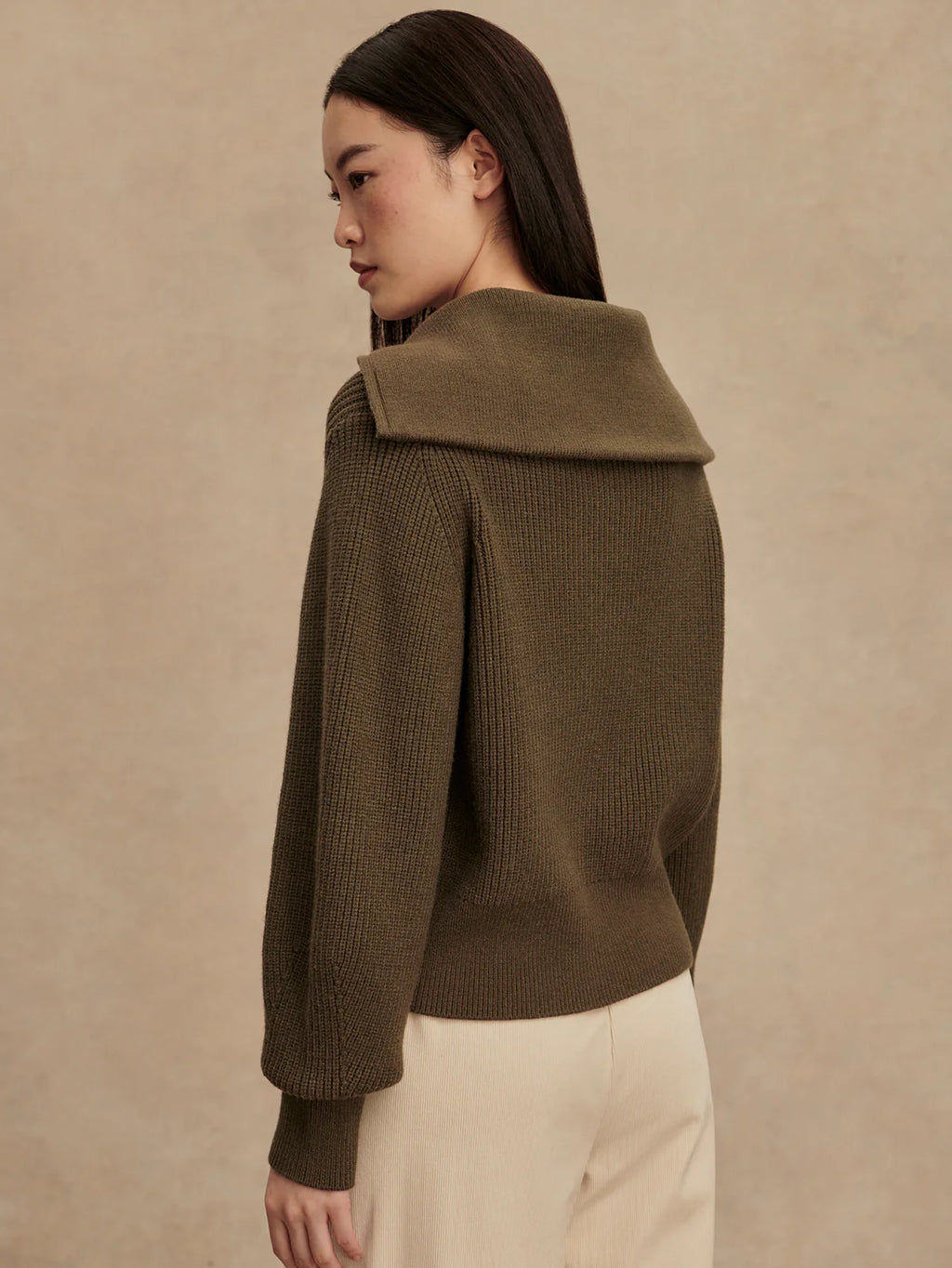 Woman wearing a brown knitted sweater against a beige background