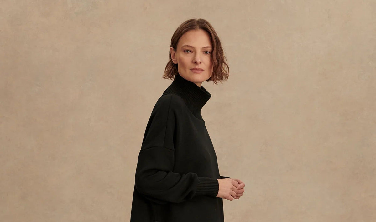 Woman wearing a black turtleneck sweater against a beige background