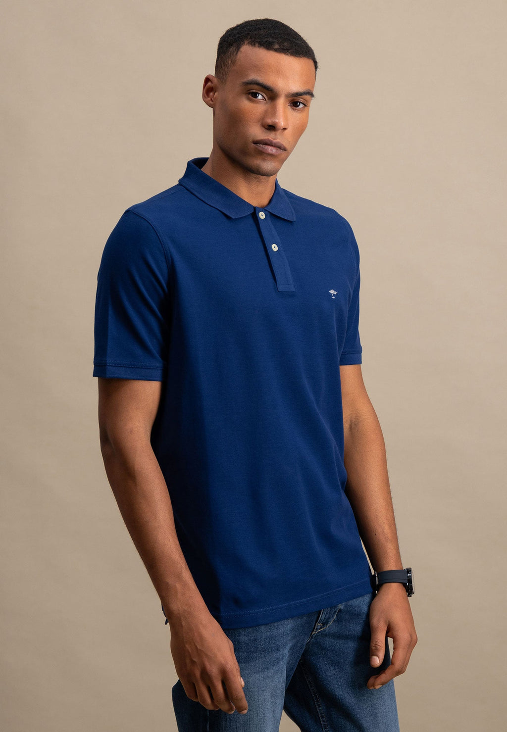 Man wearing a blue polo shirt against a beige background