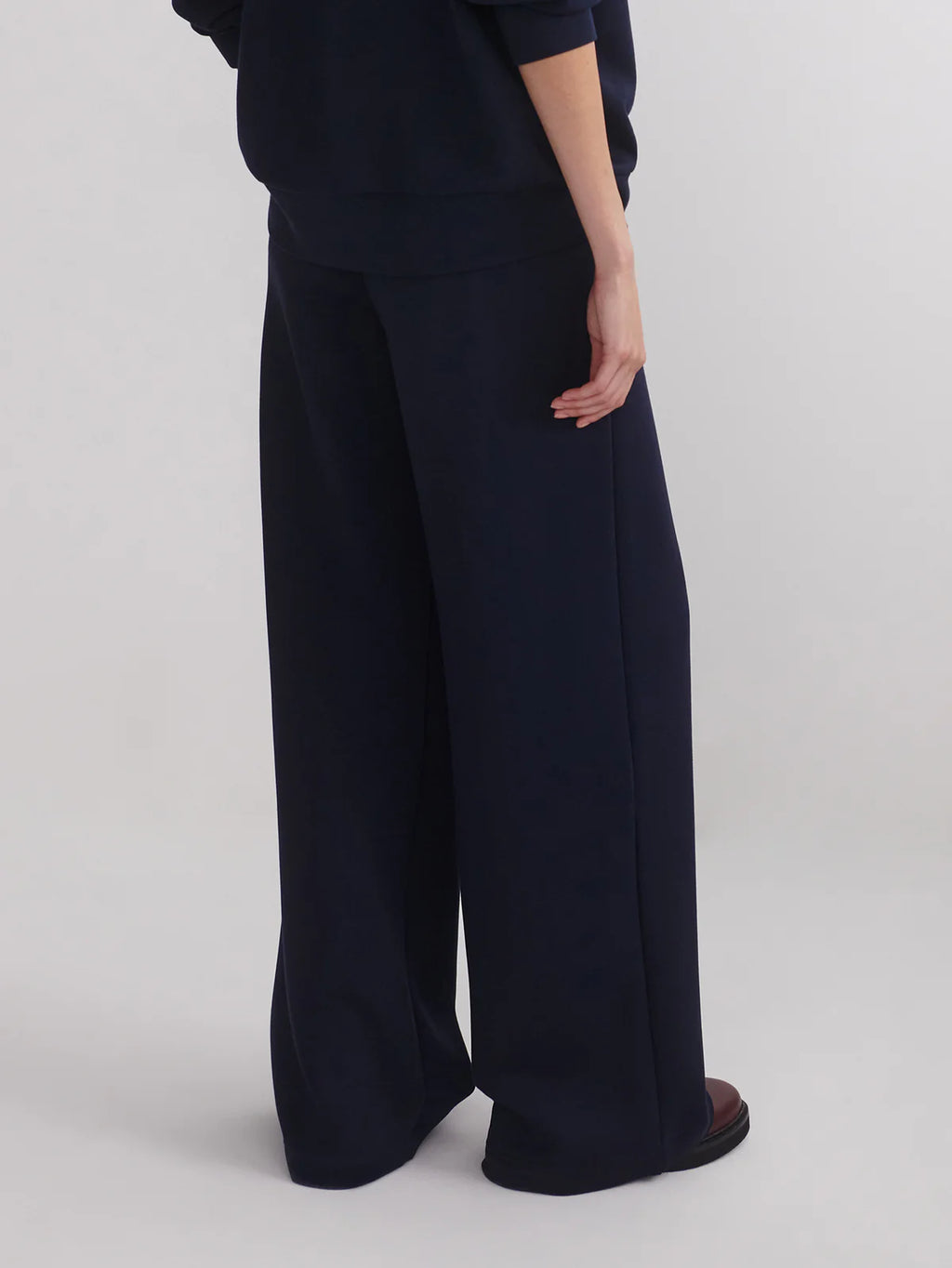 Person wearing navy wide-leg pants on a white background