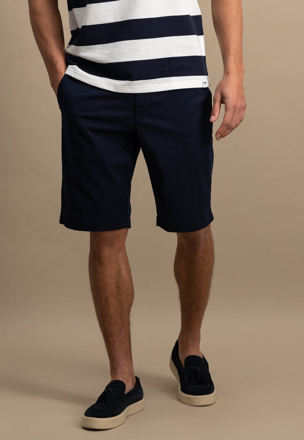 Person wearing navy shorts and a striped shirt on a beige background