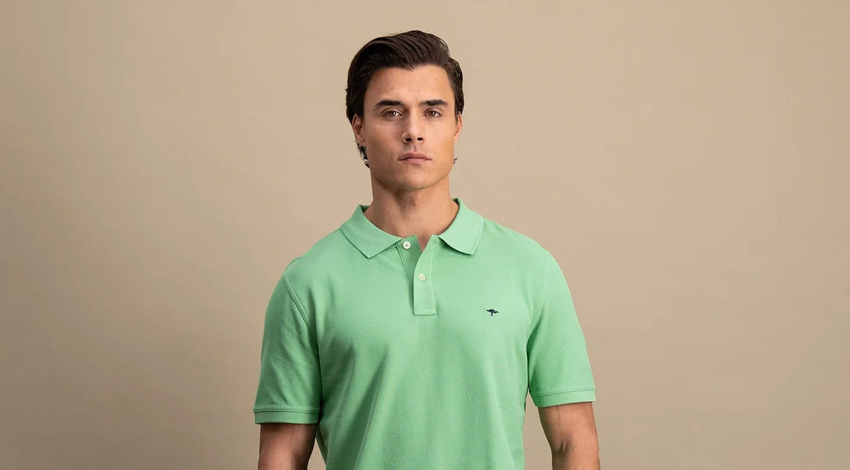 Man wearing a green polo shirt against a beige background