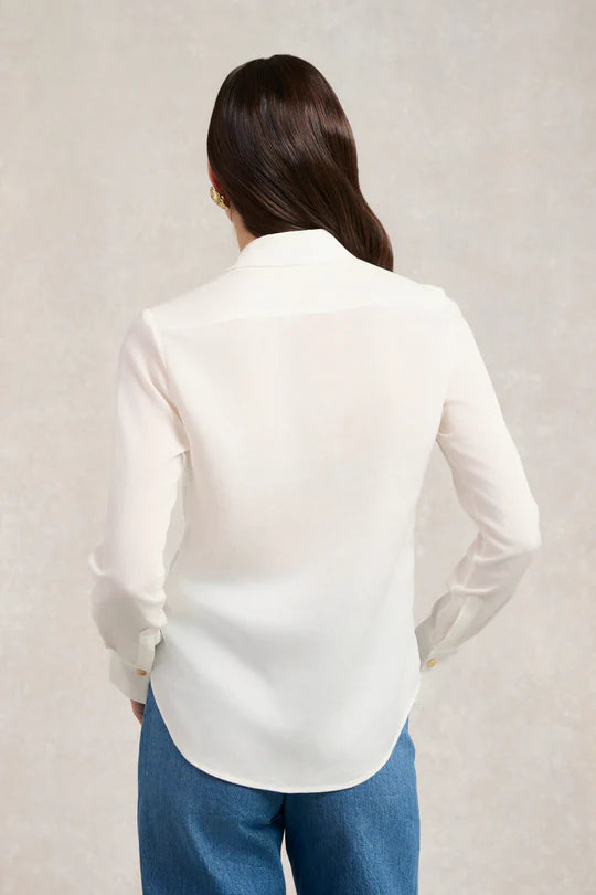 Person wearing a white shirt and blue pants against a plain background
