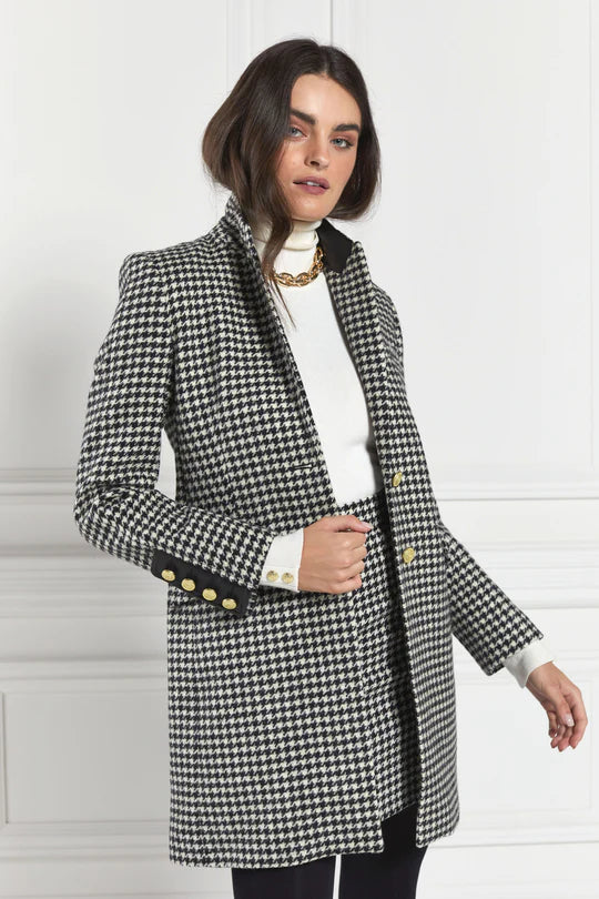 Woman wearing a checkered coat against a white wall