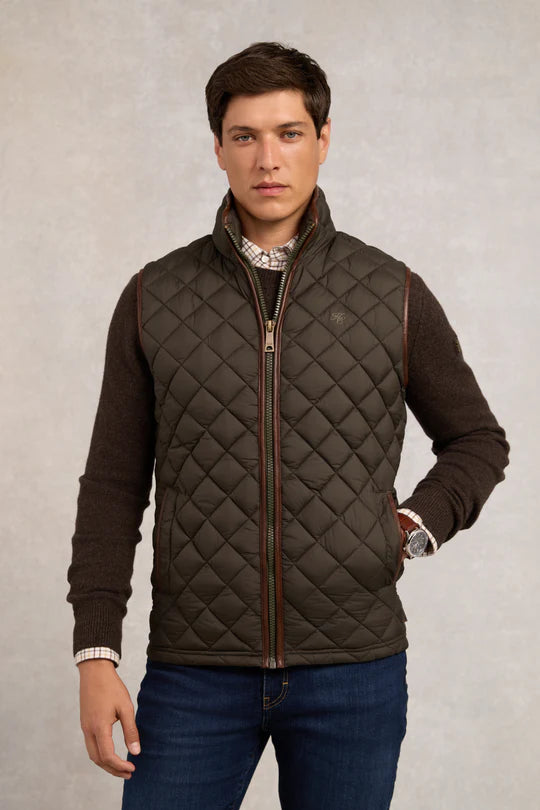 Man wearing a quilted brown jacket on a plain background