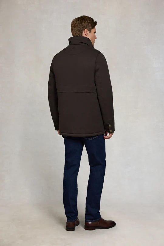 Man wearing a dark brown coat and blue jeans against a plain background