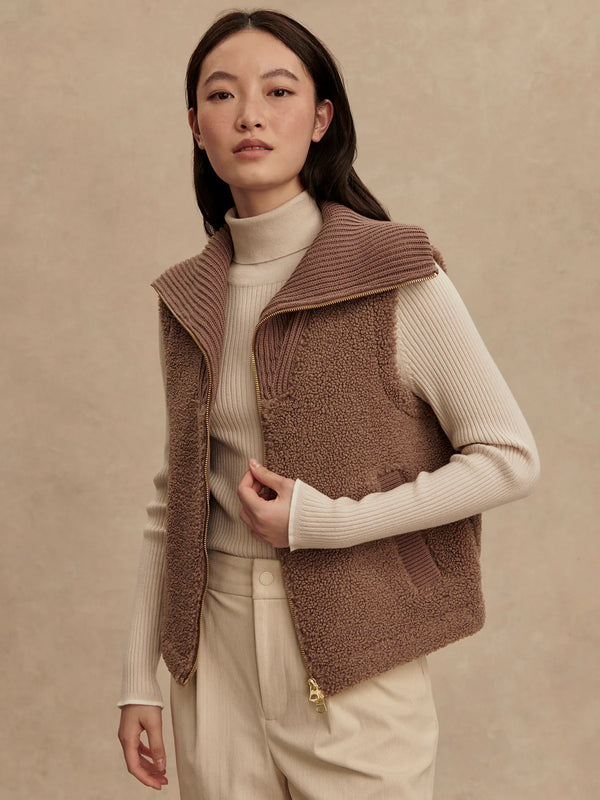 Woman wearing a brown knitted vest over a beige sweater on a beige background
