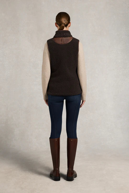 Woman wearing a brown fleece vest on a grey background