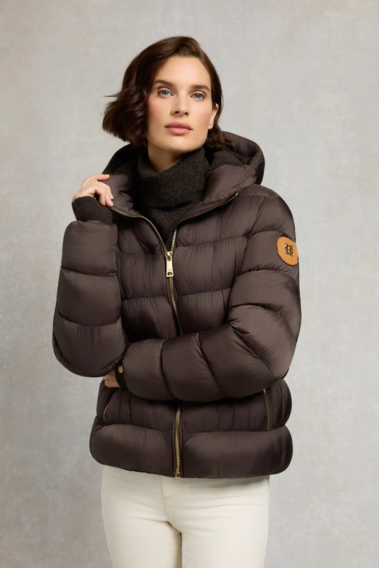 Woman wearing a brown puffer jacket with a brand logo on a gray background