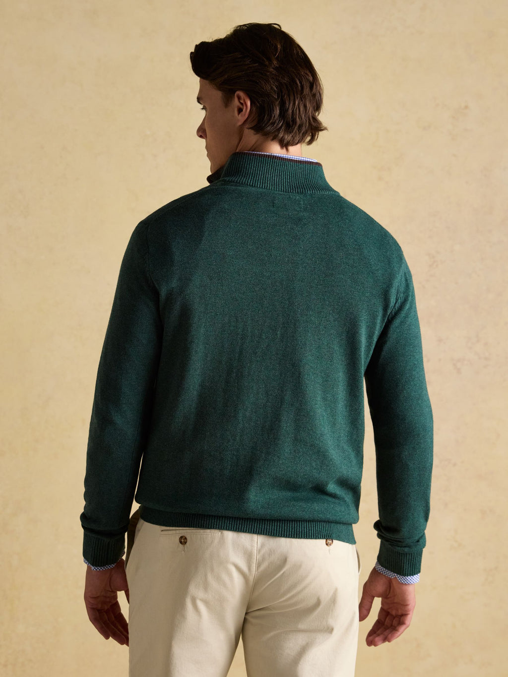 Man wearing a green sweater against a beige background