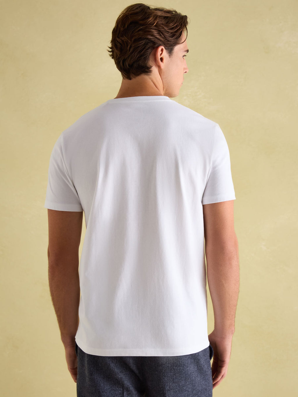 Man wearing a plain white t-shirt against a beige background