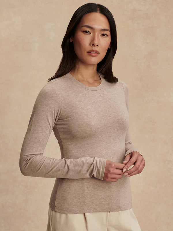 Woman wearing a beige long-sleeve top against a beige background