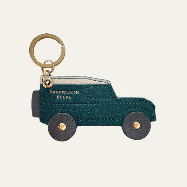 Teal car-shaped keychain with gold accents on a beige background