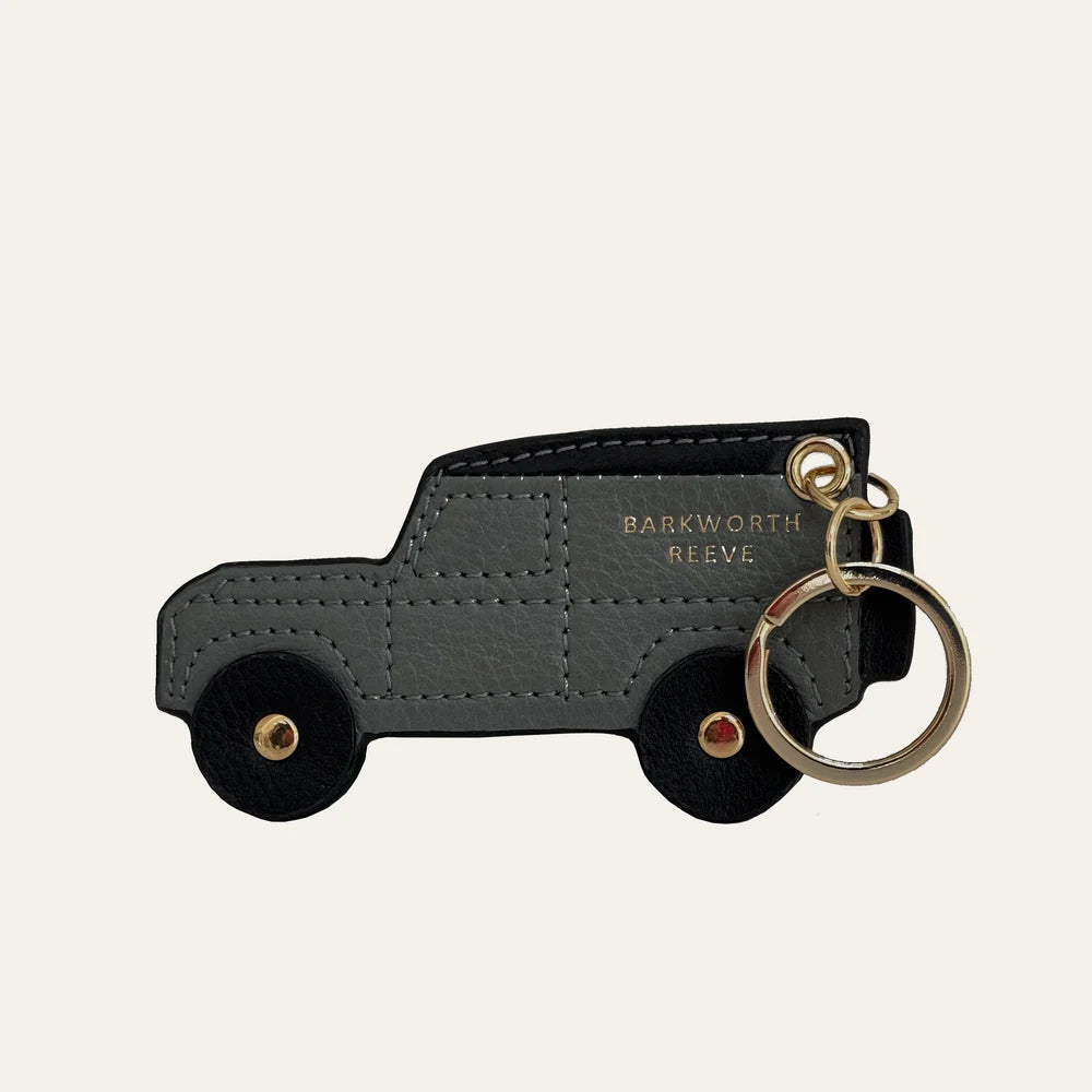 Black truck-shaped keychain with a bottle opener on a beige background