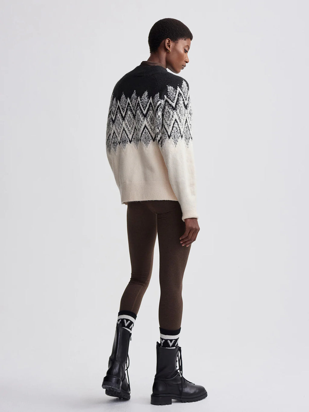 Person wearing a black and white patterned sweater on a white background