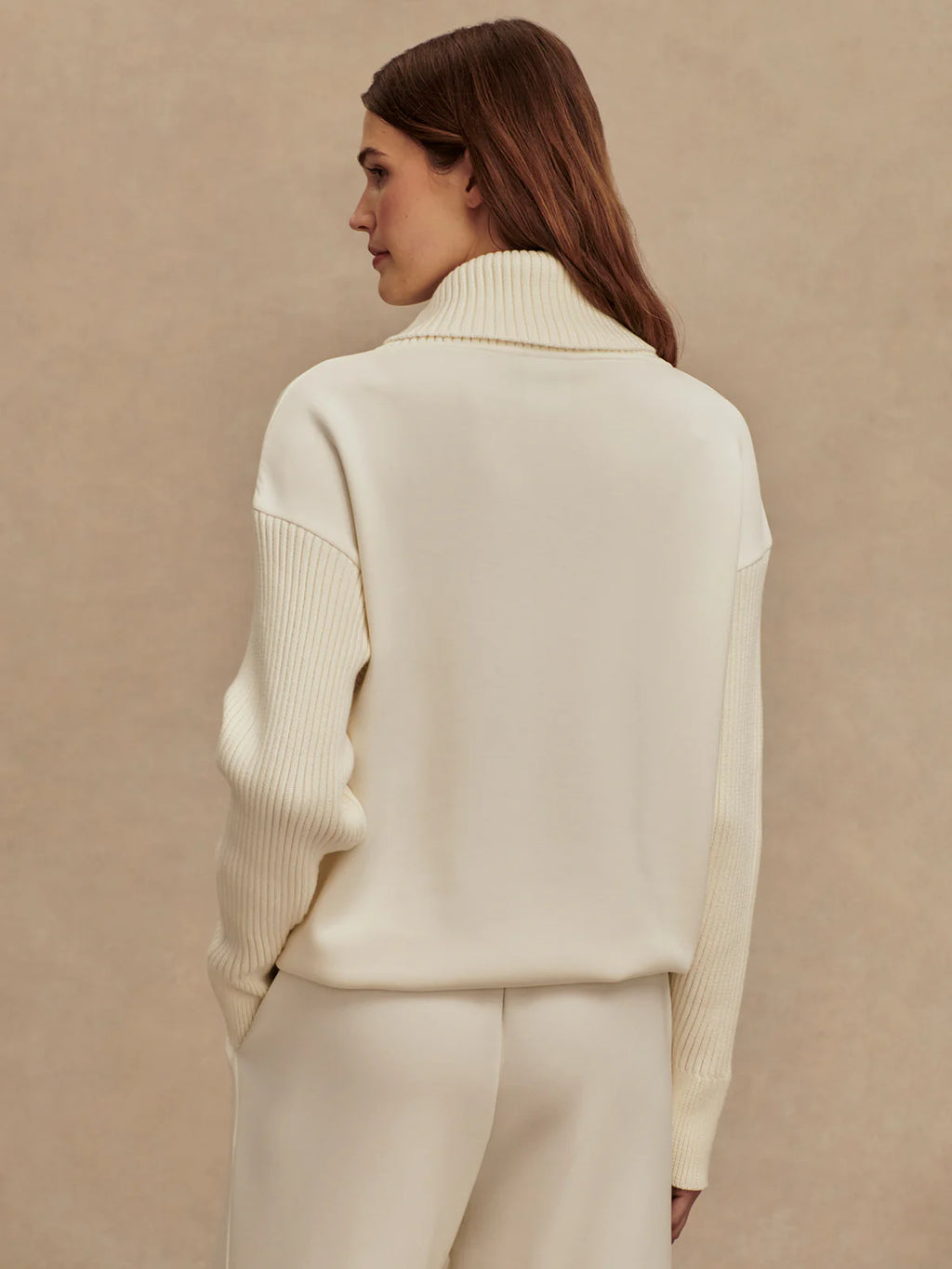 Woman wearing a cream-colored outfit against a beige background