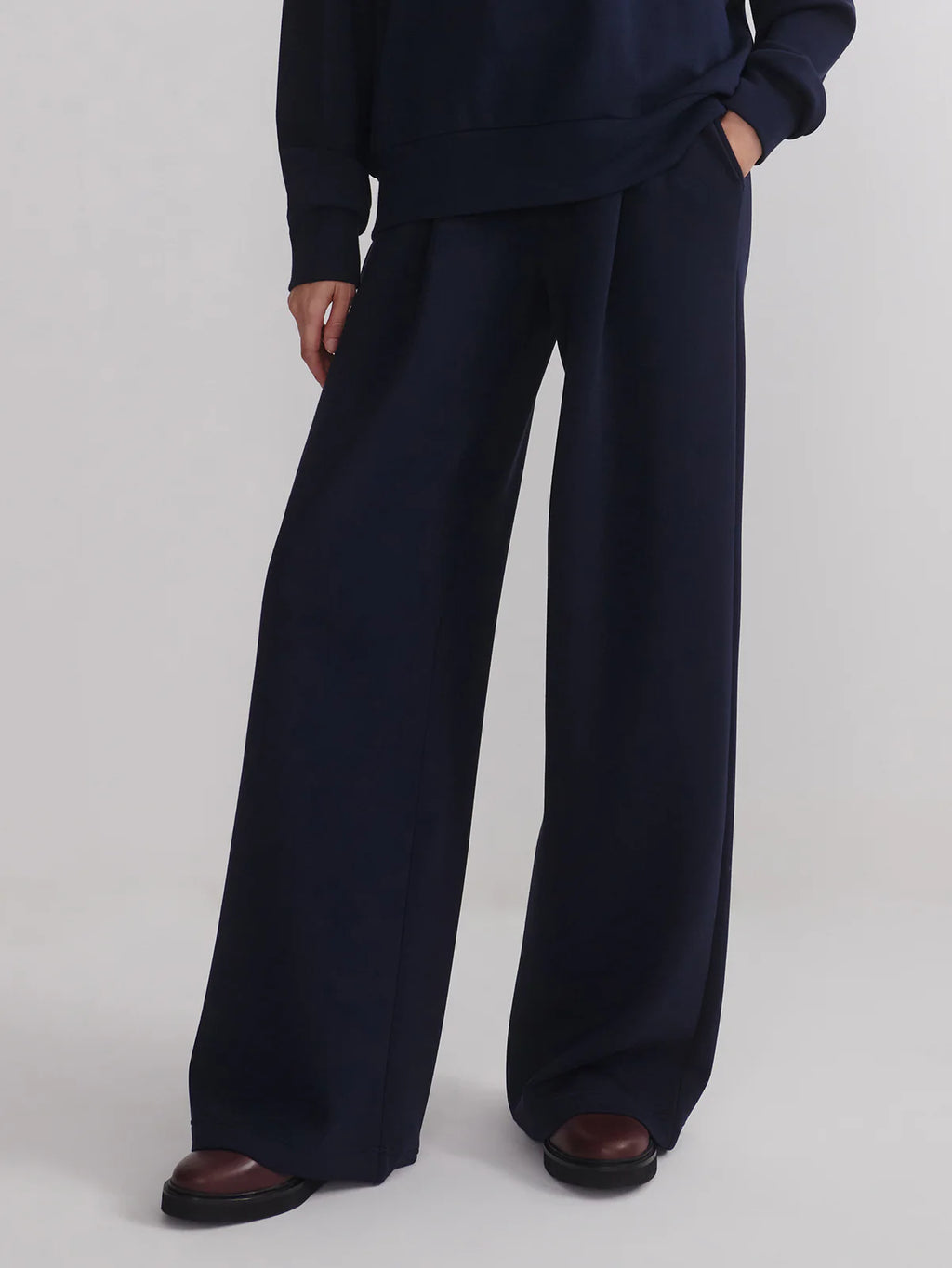 Person wearing navy wide-leg pants on a white background