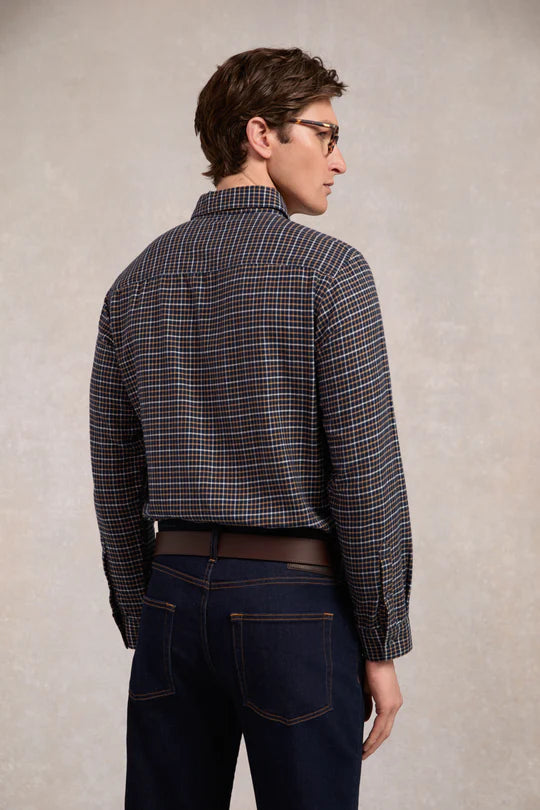 Man wearing a checkered shirt and dark jeans against a plain background