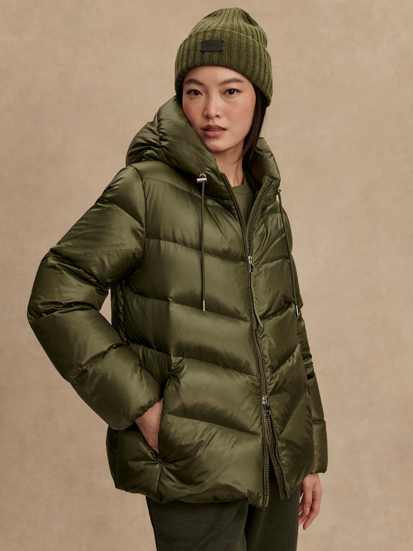 Person wearing a green puffer jacket and beanie against a beige background