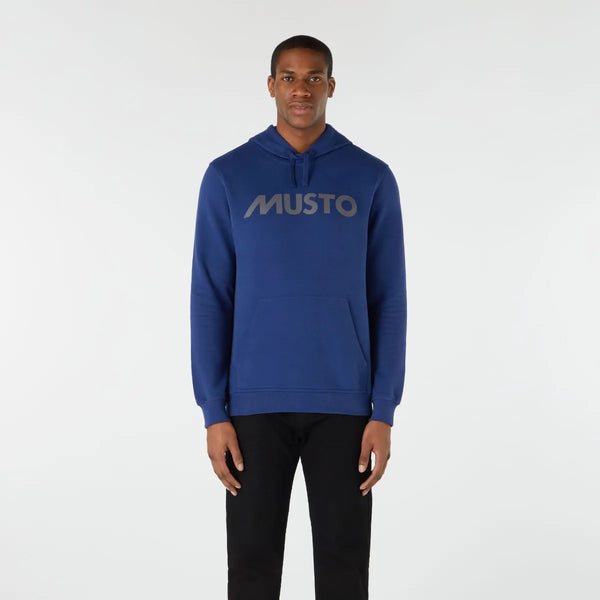 Person wearing a blue hoodie with 'MUSTO' logo on a white background