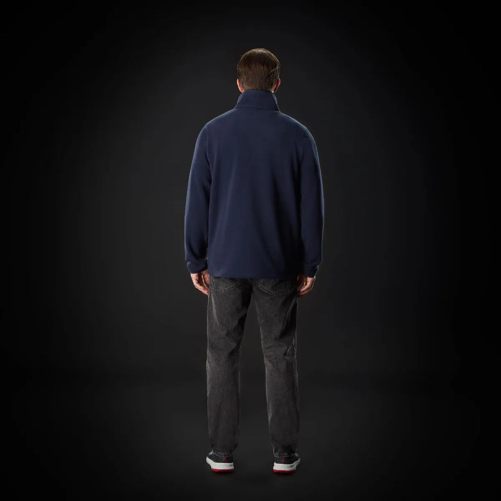 Person wearing a navy blue jacket and dark pants on a black background