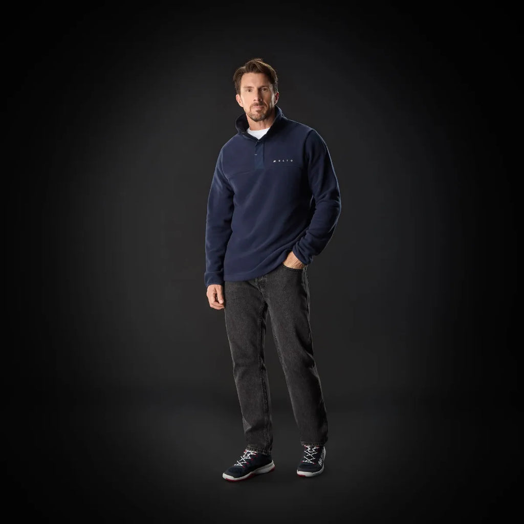 Man wearing a navy blue sweater with a logo on a black background