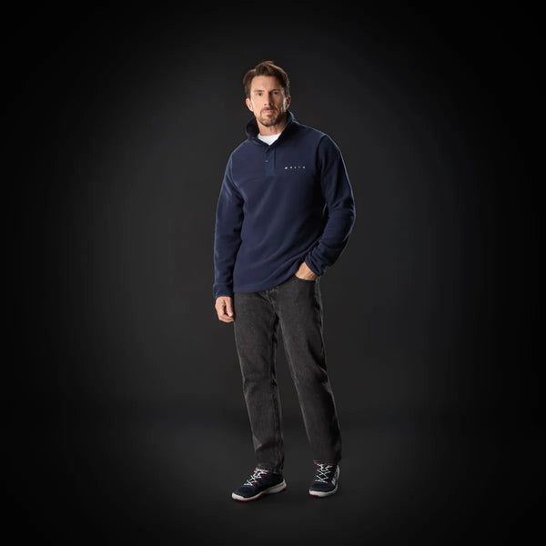 Man wearing a navy blue sweater with a logo on a black background