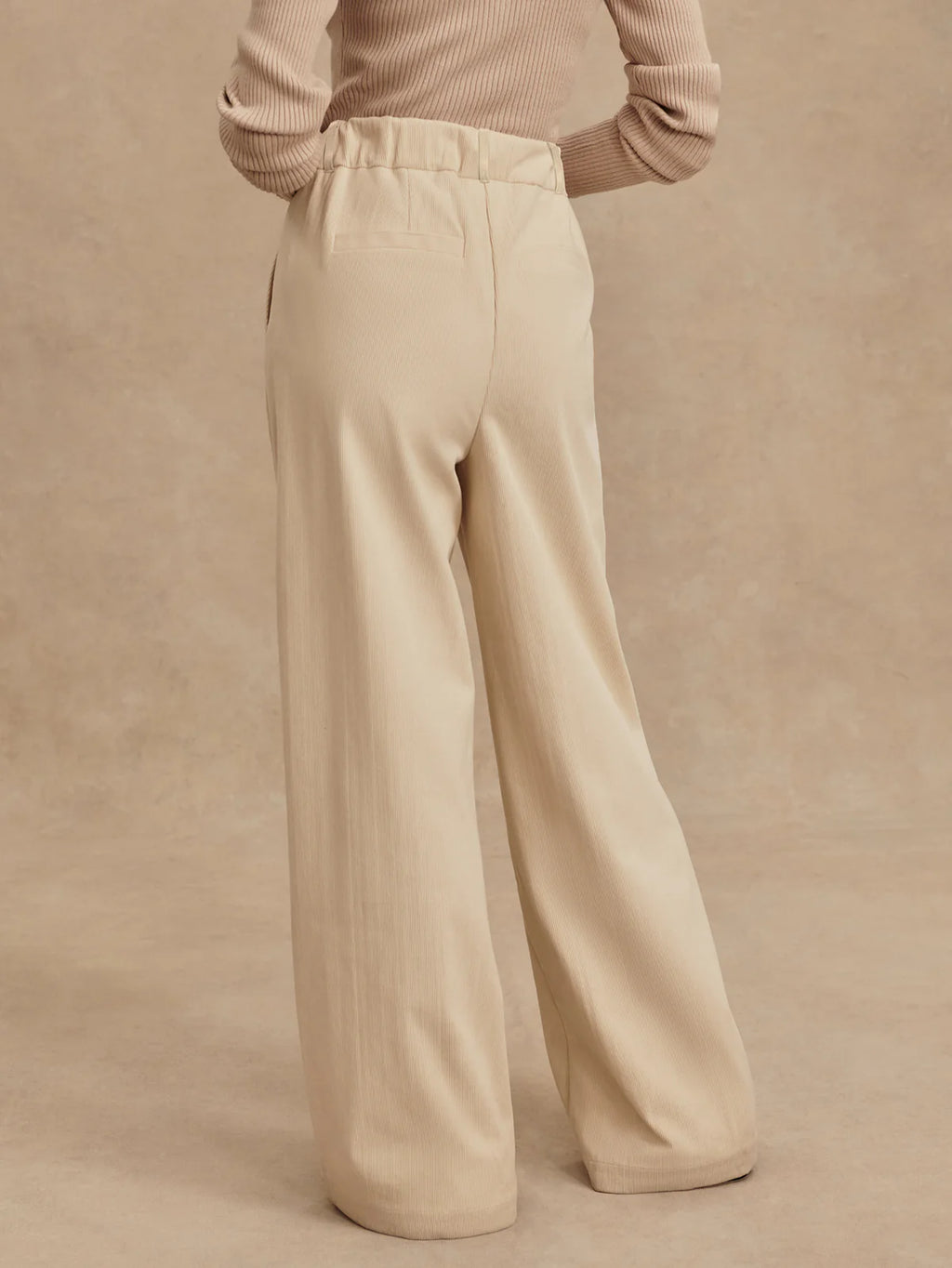 Beige wide-leg pants worn by a person on a beige background
