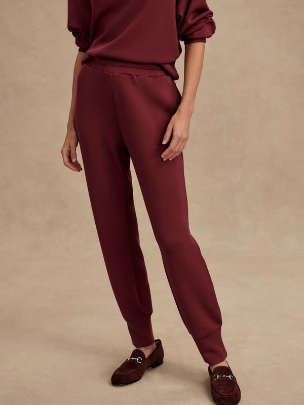 Maroon outfit with pants and loafers on a beige background